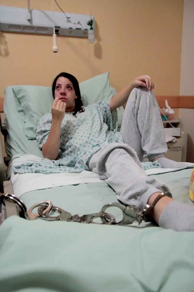 Una mujer esposada en una cama de hospital.