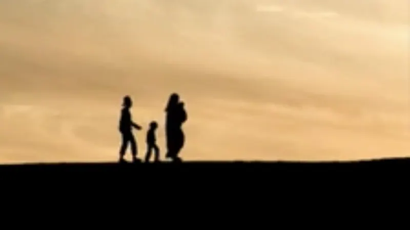 Tres siluetas en una loma bajo un cielo ámbar.