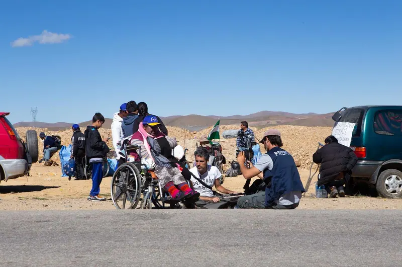 Marchistas descansan al borde del camino bajo un cielo azul intenso. La marcha a La Paz, Bolivia, 2016.
