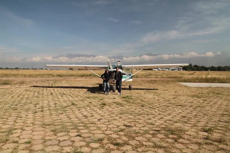 Dos personas junto a una avioneta en una pista seca.
