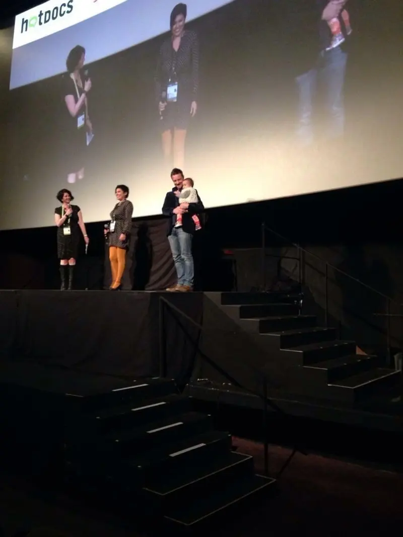 Un equipo de cine responde preguntas en el escenario, bajo una pantalla con el logo de Hot Docs.