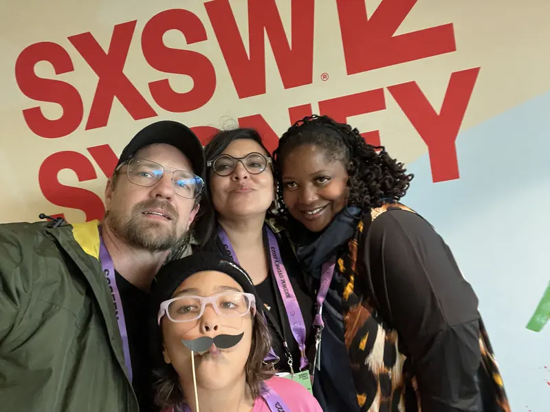 Tres personas se toman una selfie frente a un letrero de SXSW Sydney.