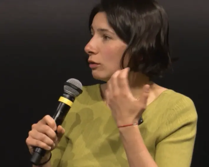 A speaker in a green top talks into a microphone.