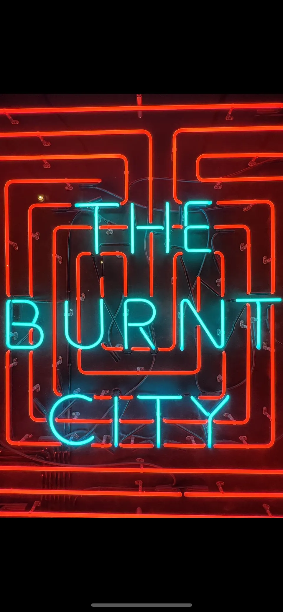 Un letrero de neón rojo y azul que dice The Burnt City.