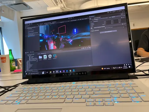 Una laptop muestra una escena 3D oscura con luces de neón, en un motor de videojuegos.