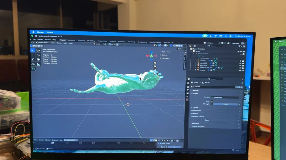 Un monitor muestra un modelo de gecko turquesa echado de espaldas en Blender.