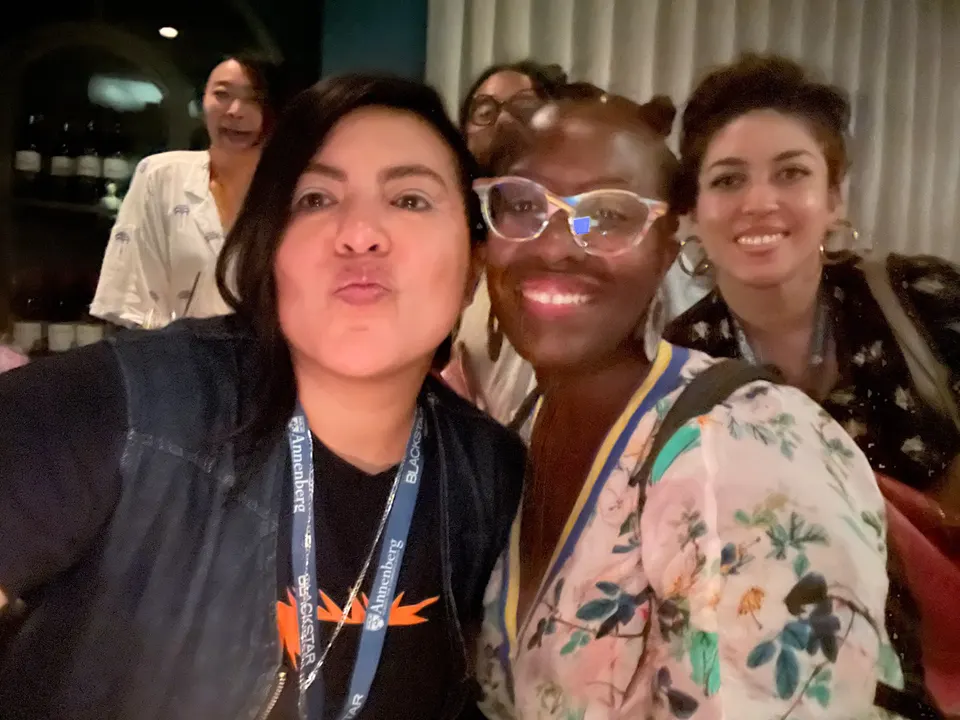 Cuatro personas sonríen cerca de la cámara para una selfie. Dos de ellas llevan credenciales del festival.